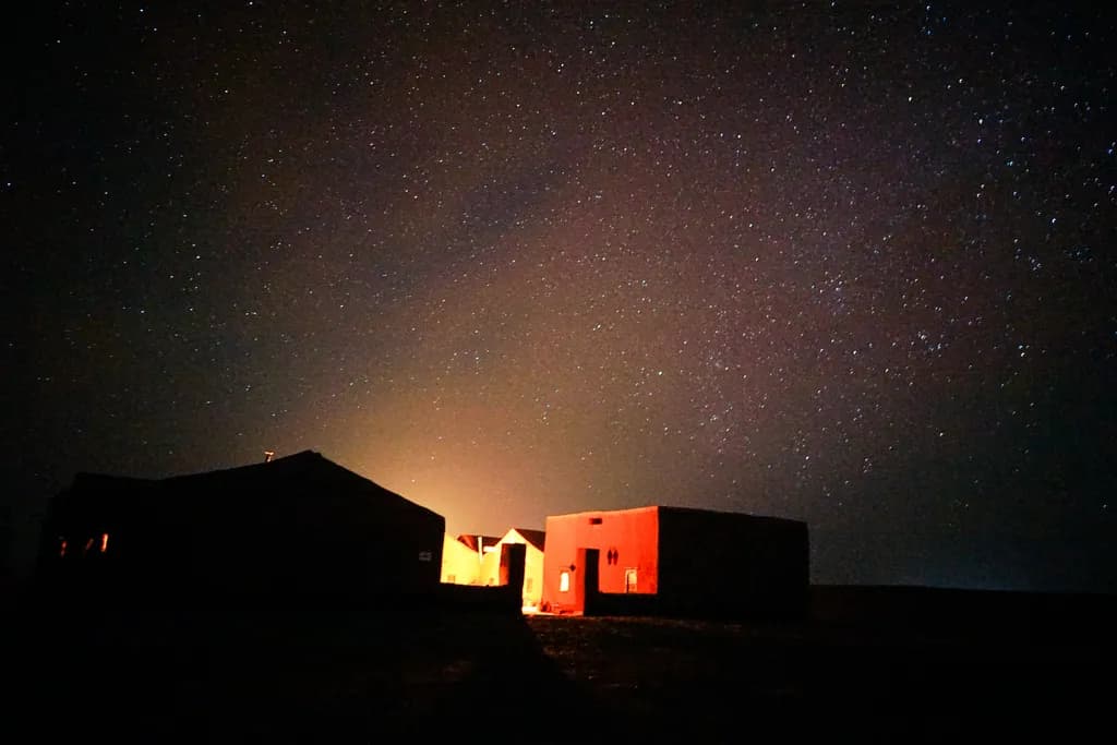 Whispers of the Night: A Cosmic Embrace Over Rustic Shelters