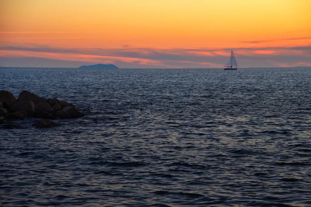 Serenity at Dusk: A Sailboat's Journey Across the Tranquil Ocean Sunset