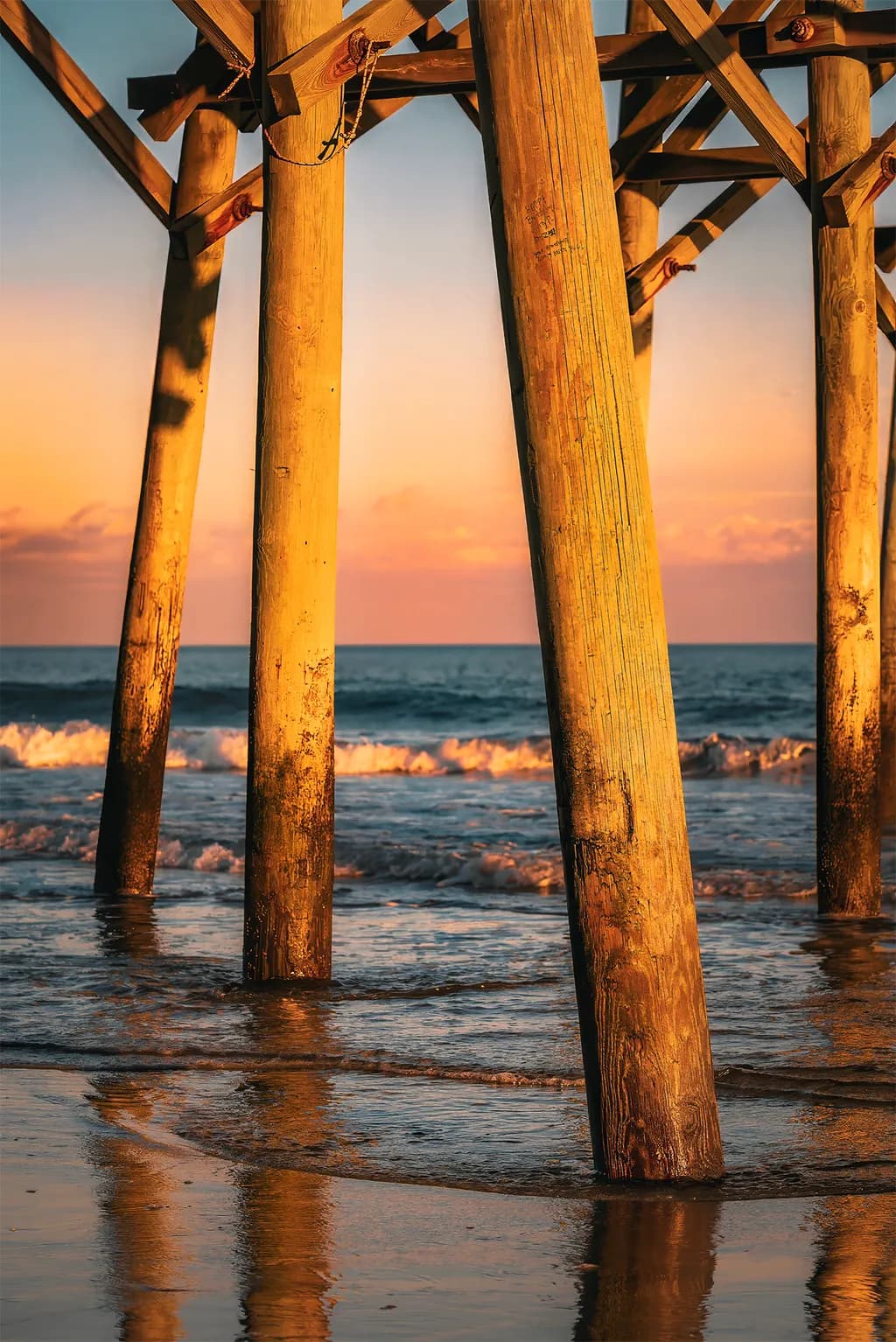 Golden Reflections: A Sunset Pier Embrace Over Ocean Waves