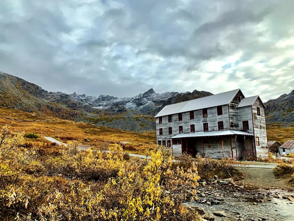 Whispers of Time: The Abandoned Lodge Amidst Majestic Peaks and Golden Foliage