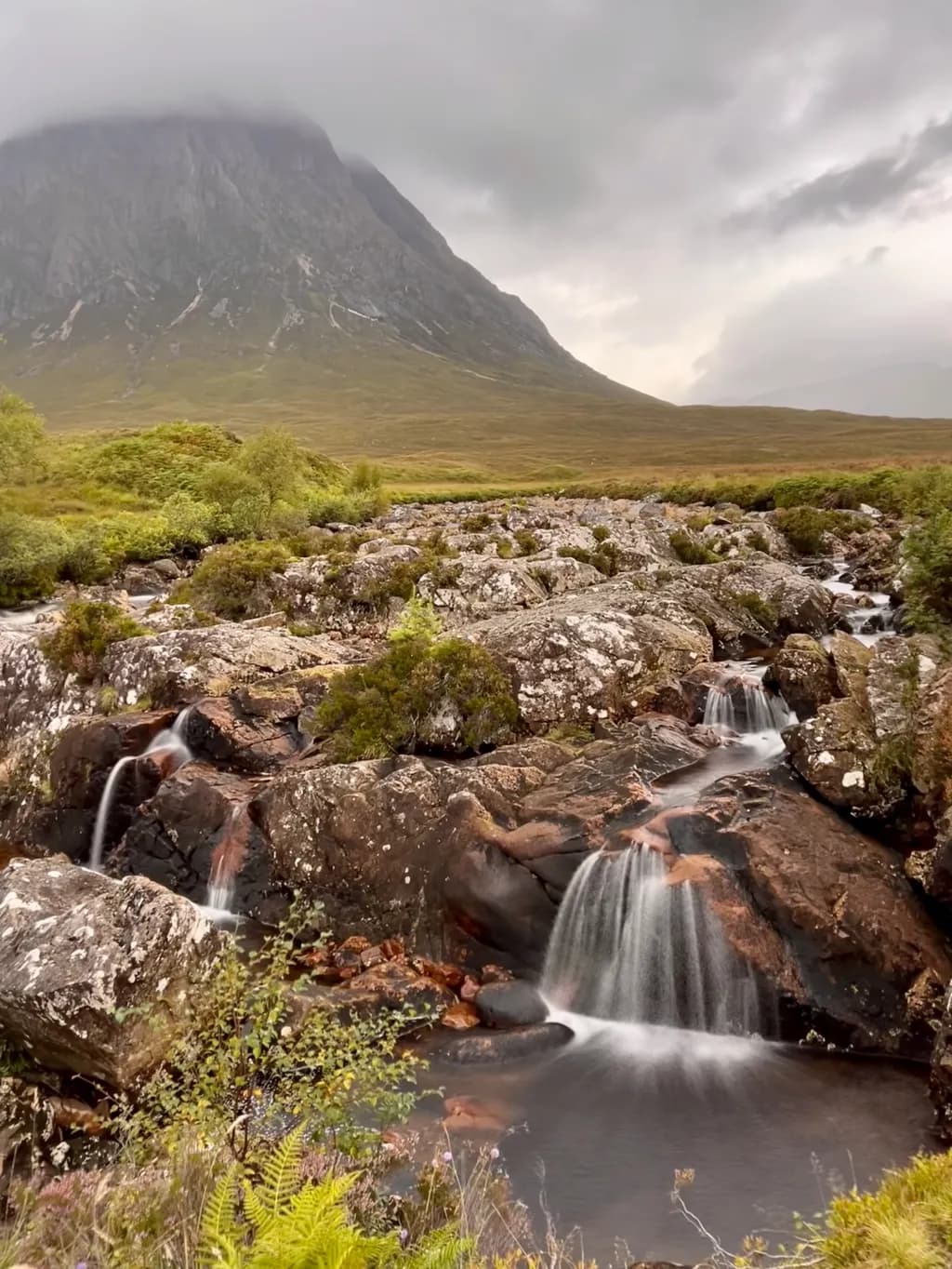 Serenity in the Highlands: A Majestic Waterfall Amidst Cloudy Peaks