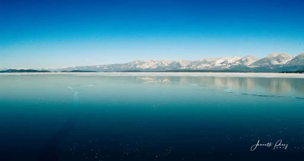 Serenity on Ice: A Tranquil Reflection of Snow-Capped Peaks and Crystal Waters