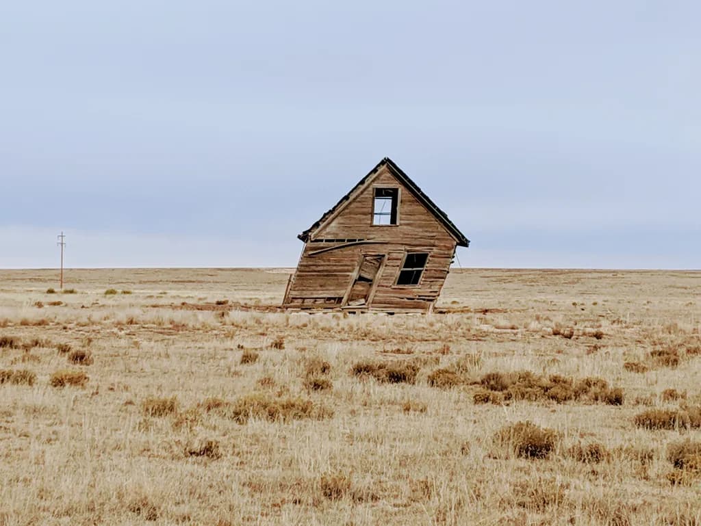 Whispers of the Past: The Leaning House in the Endless Prairie Landscape