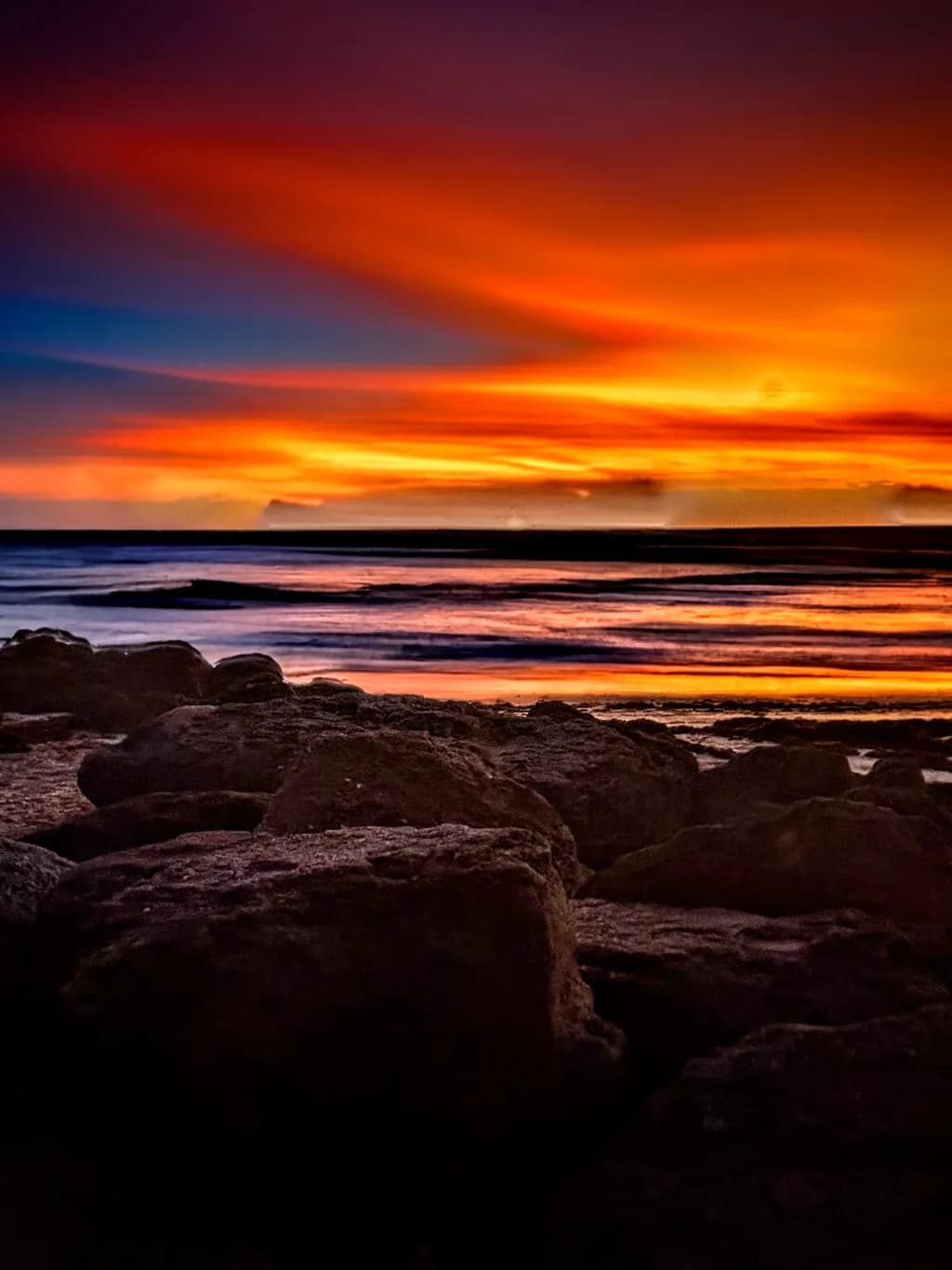 Serenity at Sunset: A Tranquil Beachscape of Vibrant Colors and Rocky Shores
