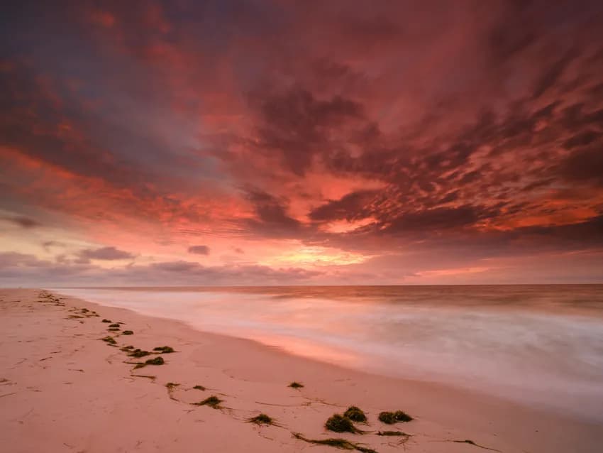Whispers of Dusk: A Serene Beach Sunset Embraced by Vibrant Skies