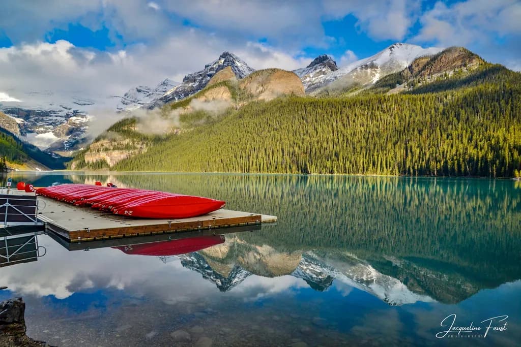 Serenity Reflected: A Tranquil Morning at Lake Louise with Red Canoes and Majestic Mountains