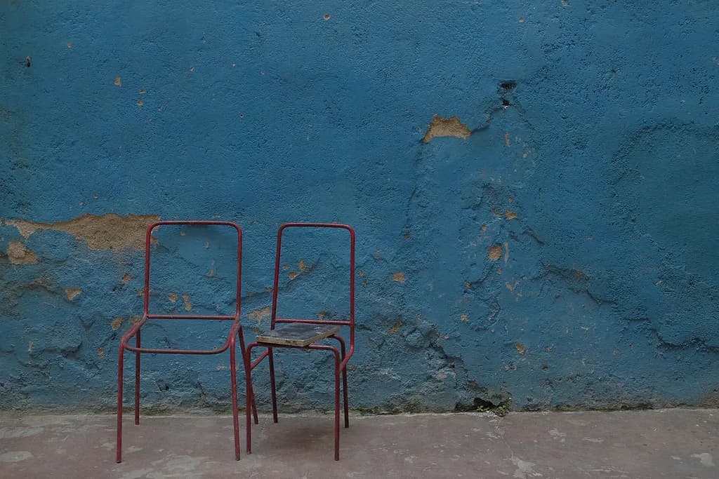 Whispers of Solitude: Two Red Chairs Against a Blue Wall