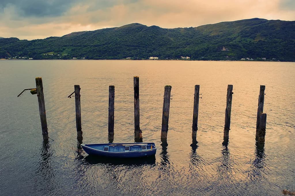 Serenity at Dusk: A Lonely Boat Amidst Weathered Pilings and Tranquil Waters