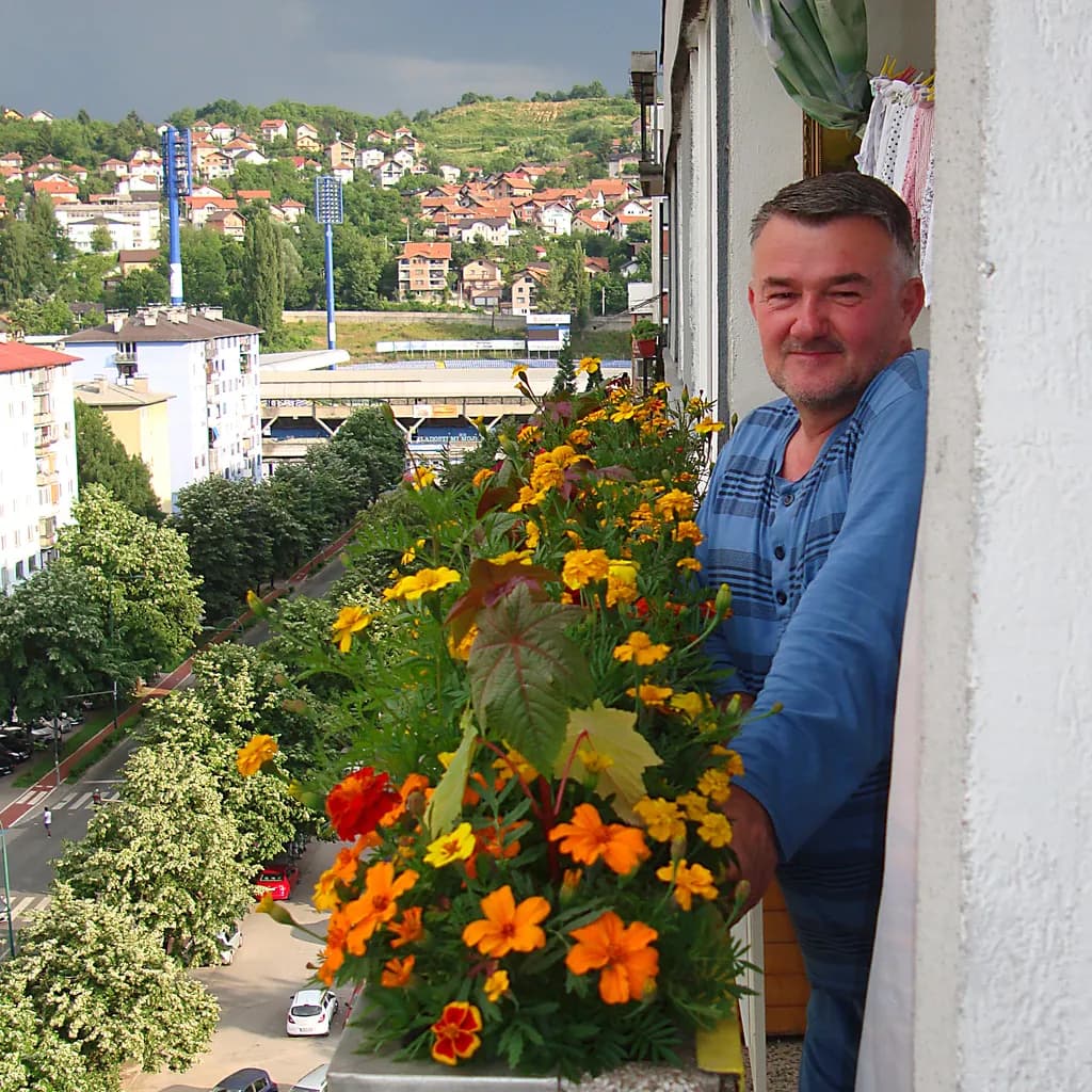 Balcony Bliss: A Man's Joy Amidst Vibrant Flowers and City Views