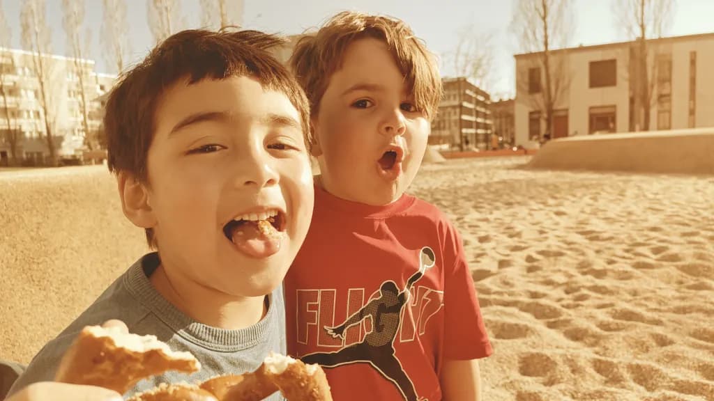 Joyful Moments: Two Boys Sharing Laughter and Treats in the Sunlit Playground