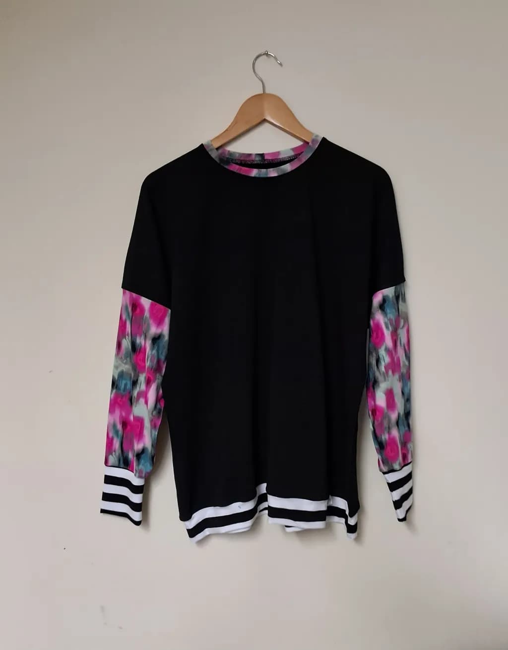 Vibrant Fusion: Black Sweatshirt with Floral Accents and Striped Cuffs