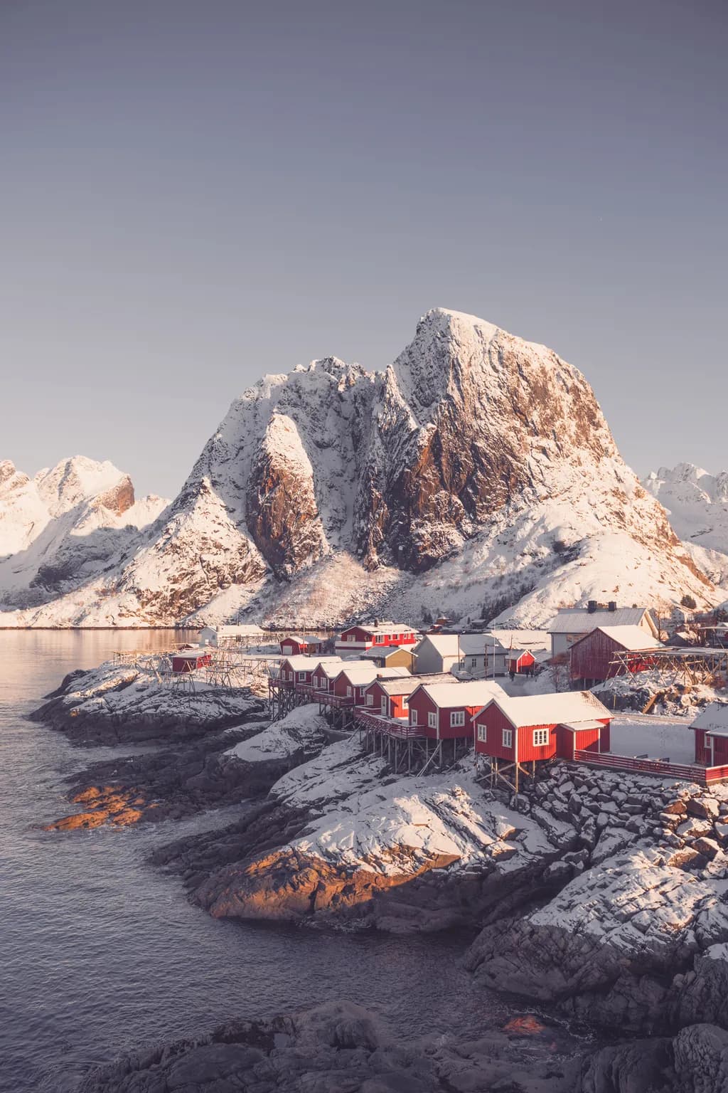 Whispers of Winter: Serene Red Cabins Against Majestic Snow-Capped Peaks in Norway