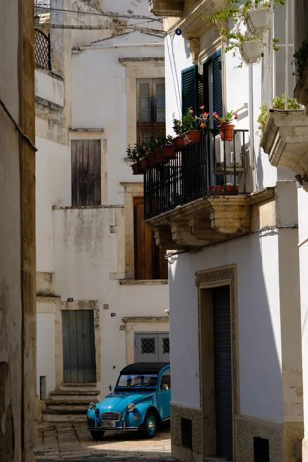 Whispers of the Past: A Serene Street Scene with a Vintage Blue Car in a Sunlit Alleyway