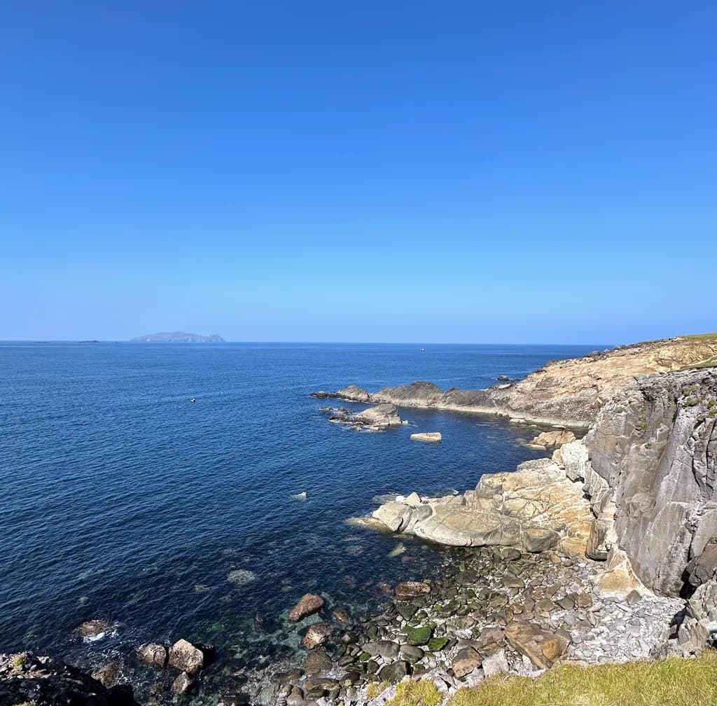 Serenity by the Coast: A Tranquil Blue Horizon Over Rocky Waters