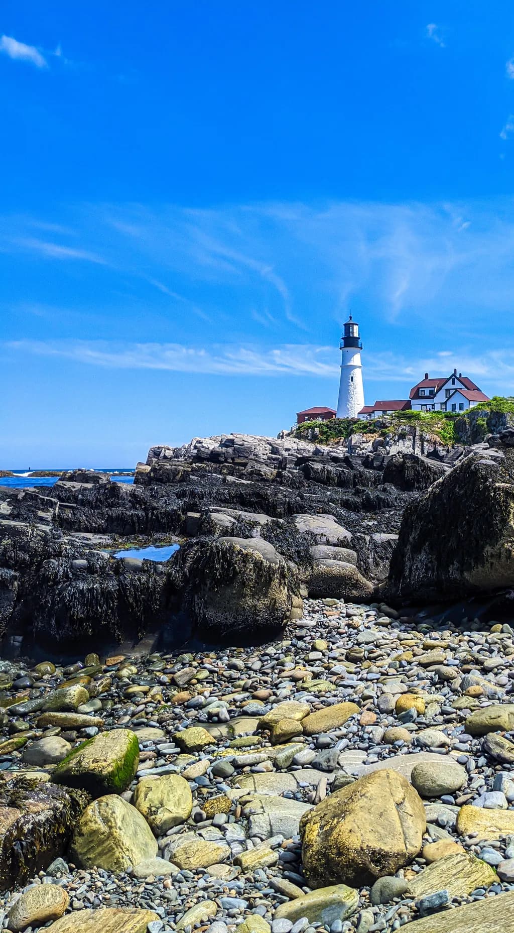 Coastal Serenity: A Lighthouse's Embrace Amidst Rocky Shores and Endless Skies