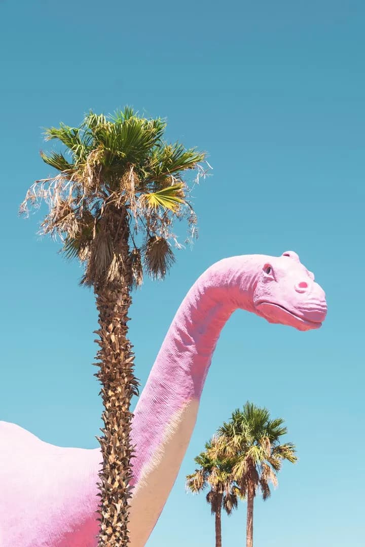 Whimsical Pink Dinosaur Beneath a Clear Sky with Palm Trees