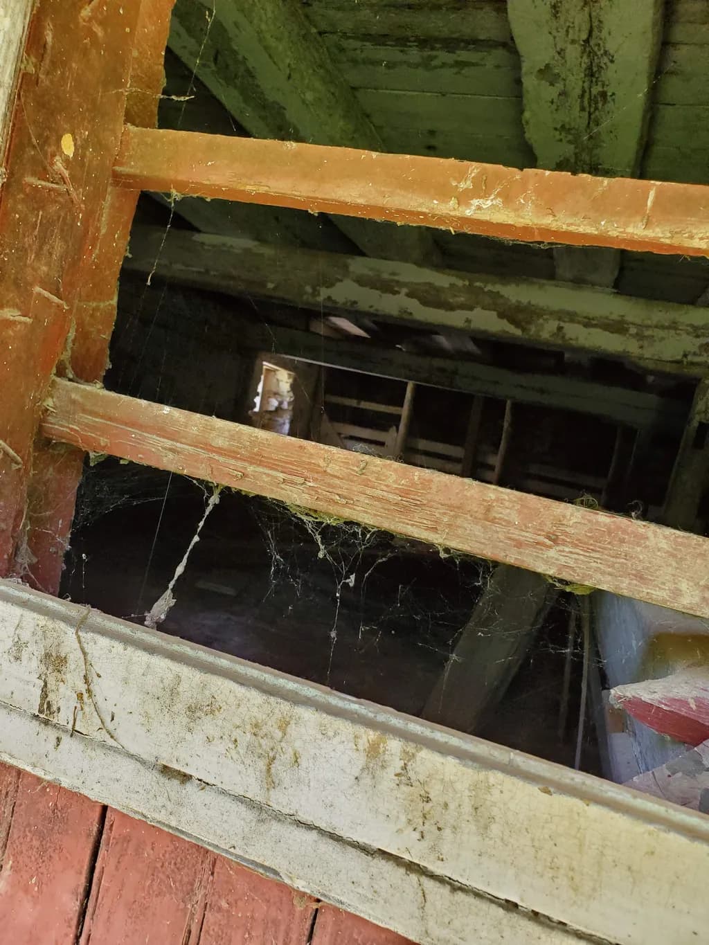 Whispers of the Forgotten: A Dimly Lit Abandoned Interior with Webs and Wooden Beams