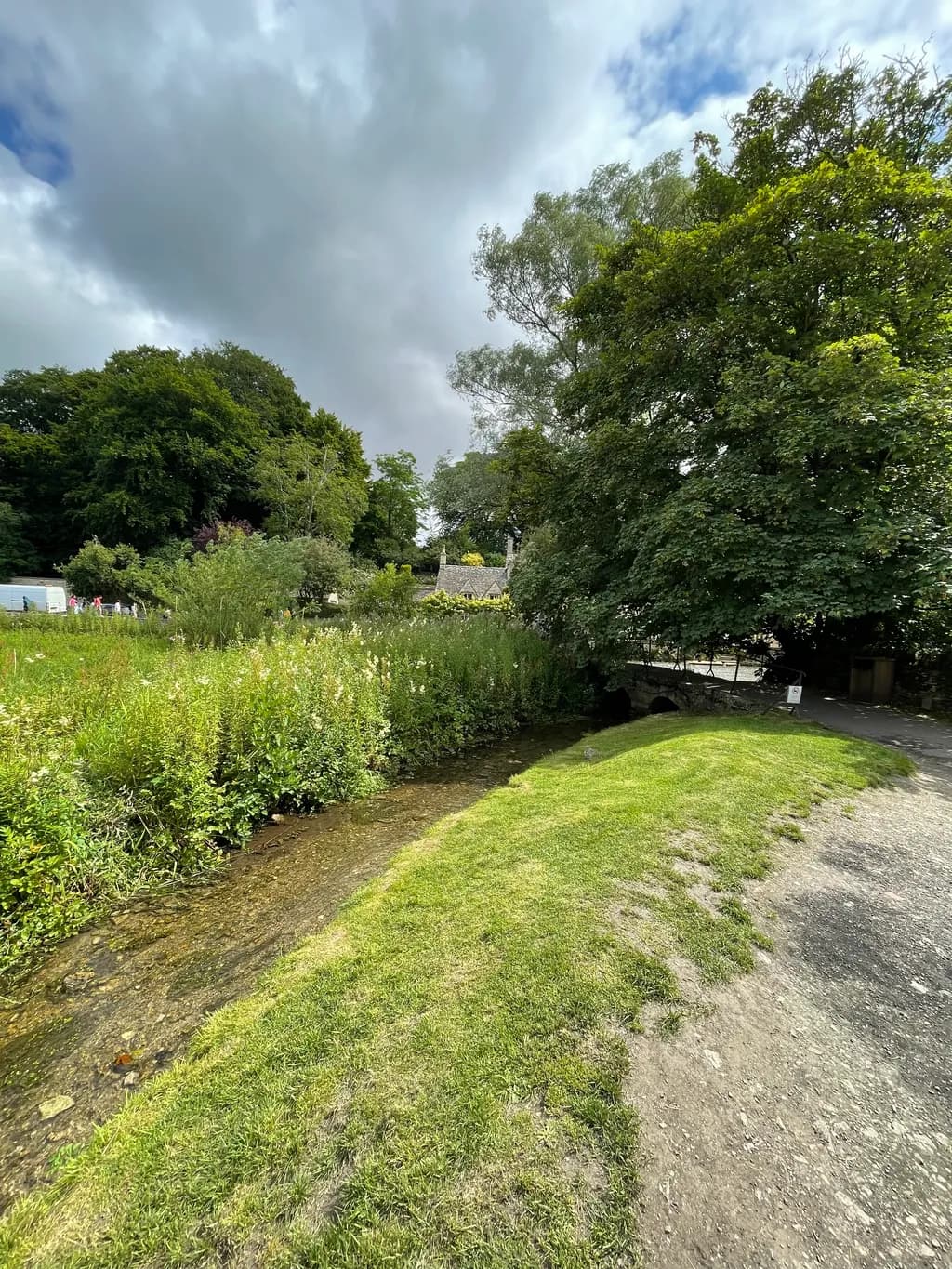 Whispers of Tranquility: A Serene Stream Embraced by Lush Greenery and Clouds