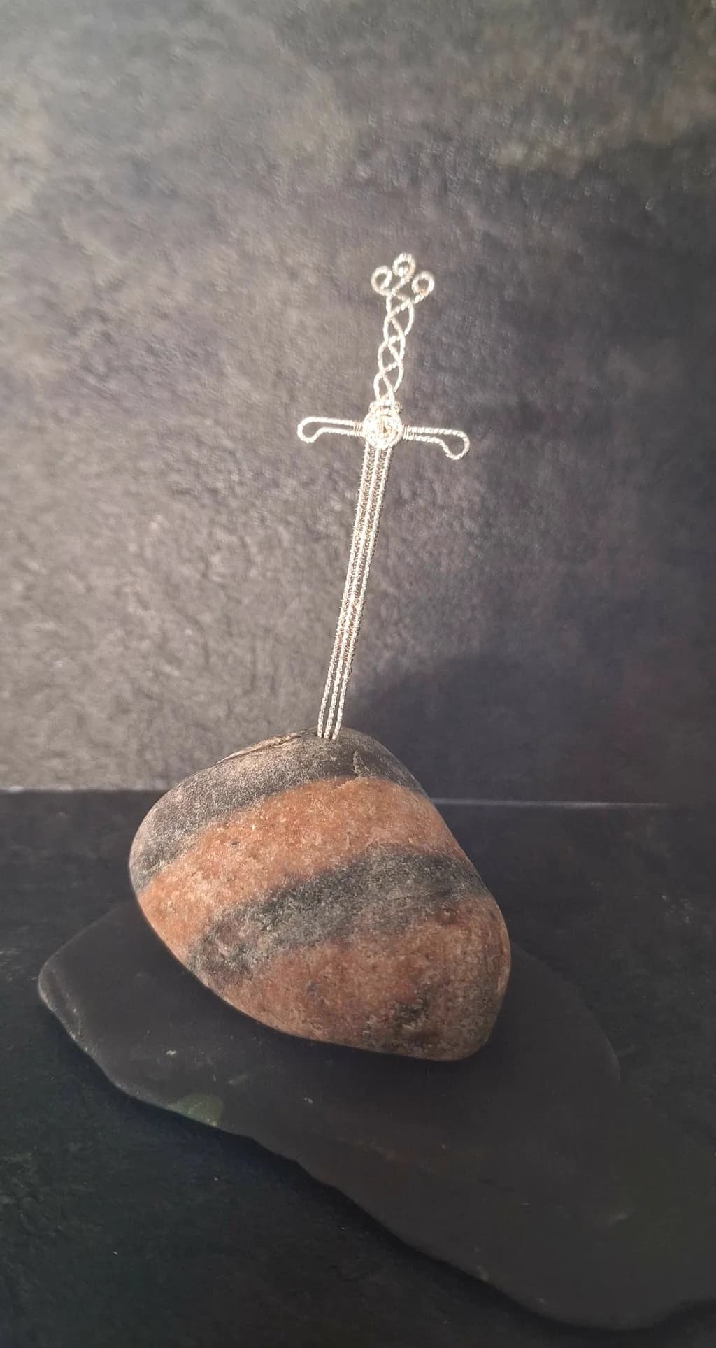 Whispers of Strength: A Wire Cross atop a Striped Stone