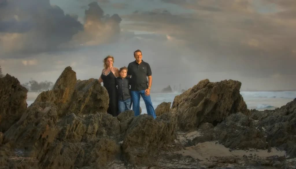 Eternal Moments: A Family Portrait Amidst Serene Beach Rocks and Dramatic Clouds