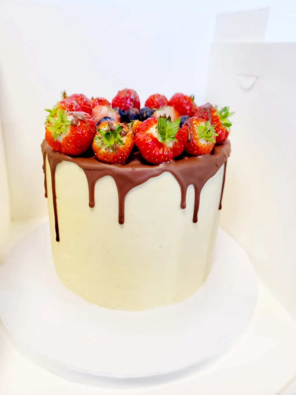 Decadent Chocolate Drip Cake Topped with Fresh Strawberries and Blueberries