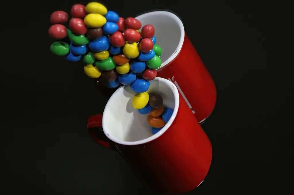 Colorful Confectionery Cascade: A Playful Dance of Candy in Red Mugs