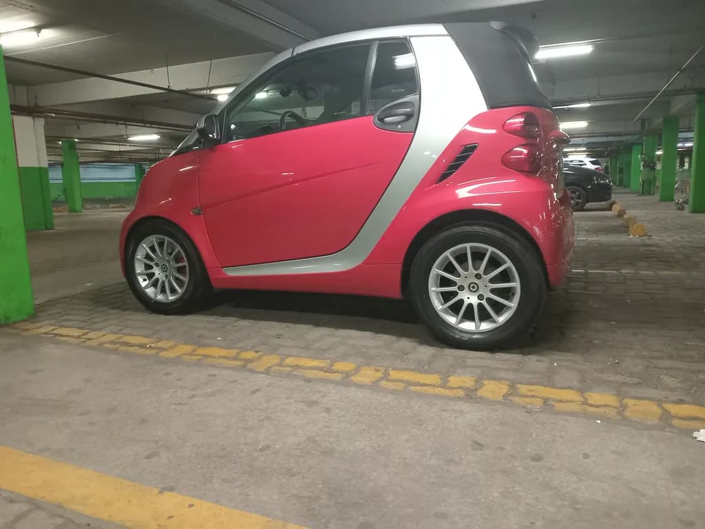 Vibrant Urban Elegance: The Pink Smart Car in a Modern Parking Space