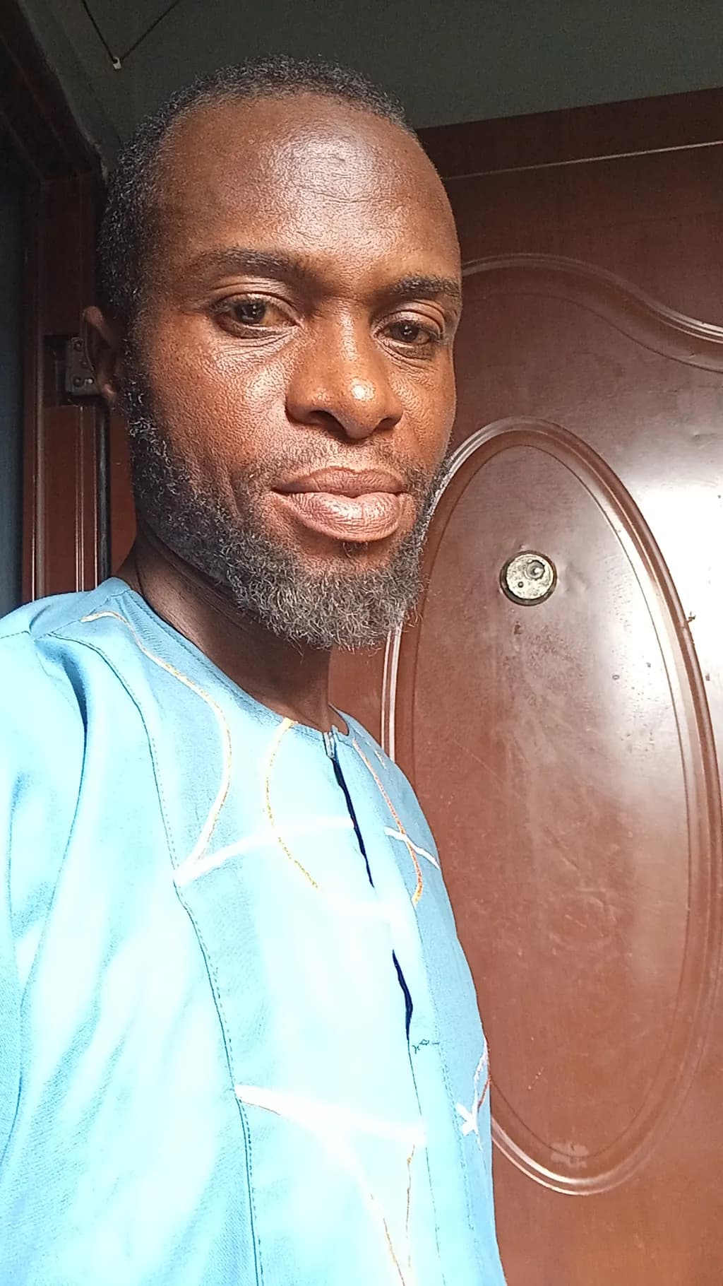 Radiant Smile: A Traditional Portrait of a Man in Blue by the Doorway