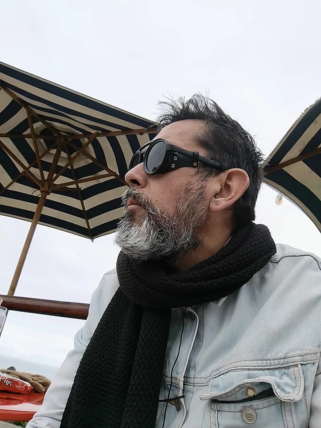 Contemplative Moments: A Man in Sunglasses Under the Umbrella