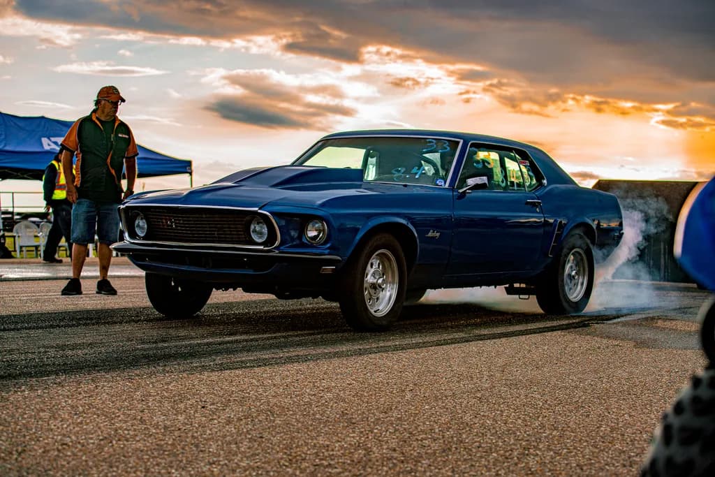 Revving Dreams: A Blue Mustang's Dance Against the Sunset Sky