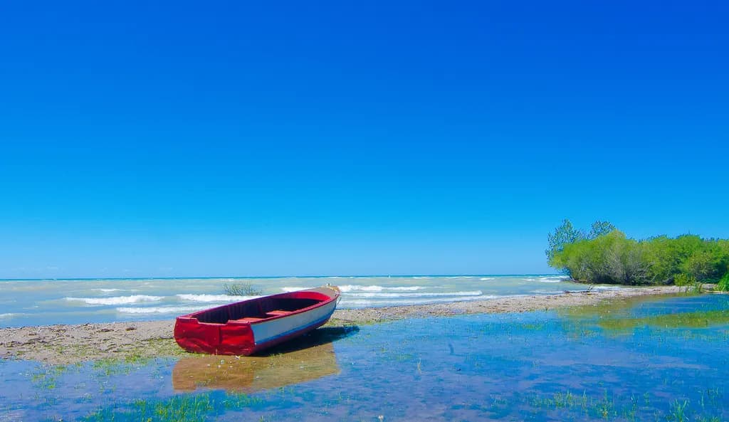 Serenity by the Shore: A Vibrant Escape with a Red Boat and Endless Blue Skies