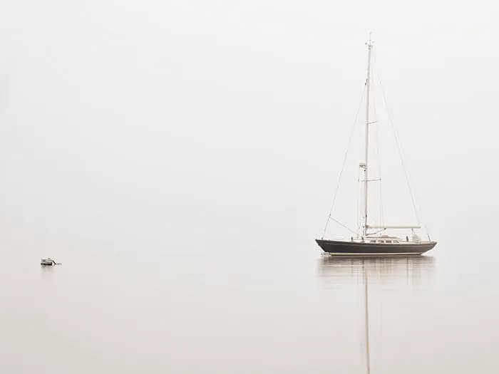 Whispers of Serenity: A Sailboat's Reflection in the Misty Horizon