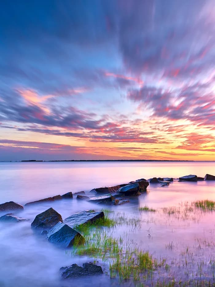Serenity at Sunset: A Tranquil Dance of Water and Rocks in Nature's Embrace