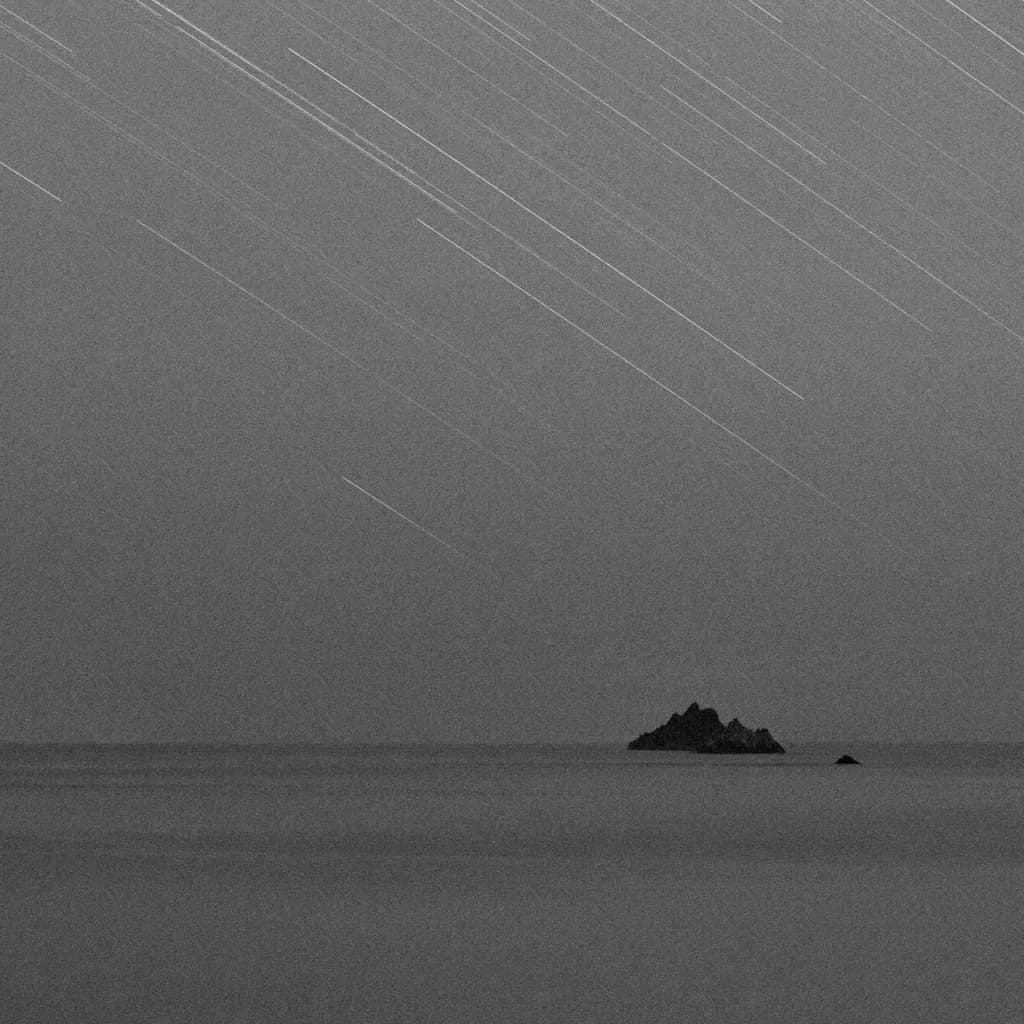 Whispers of the Night: A Monochrome Dance of Stars Over Tranquil Waters
