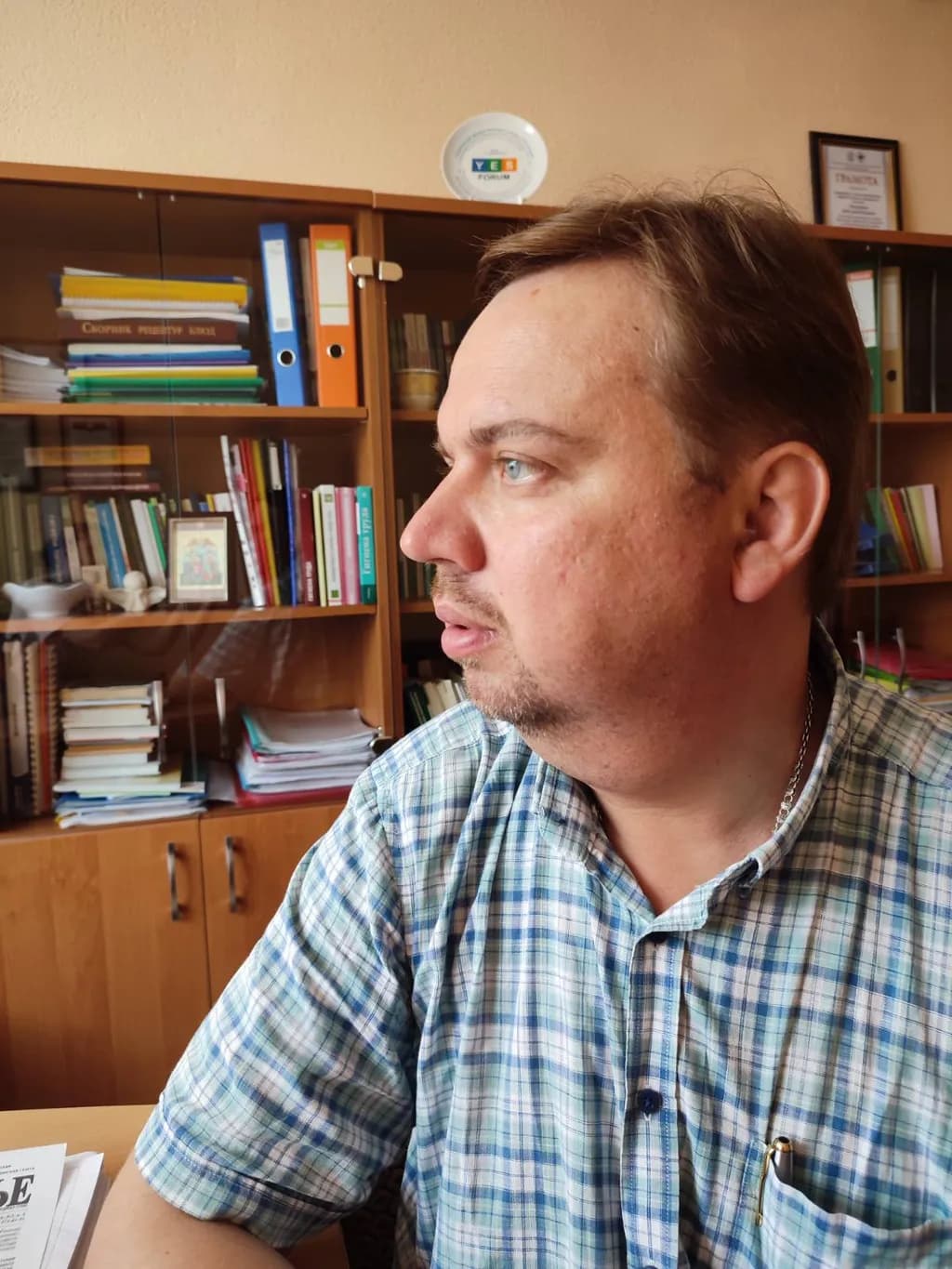 Contemplative Moments: A Thoughtful Man in a Plaid Shirt Surrounded by Books in His Office