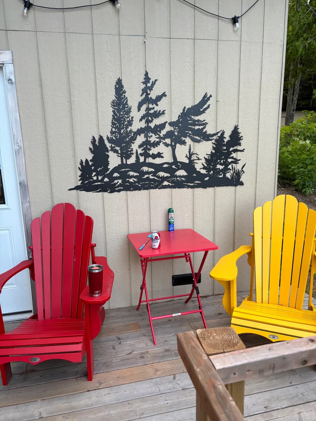 Serene Retreat: A Black Metal Forest Silhouette Above Vibrant Adirondack Chairs