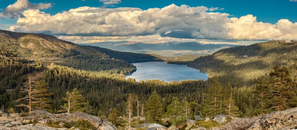 Serenity in Nature: A Majestic View of the Tranquil Lake Surrounded by Lush Forests and Dramatic Skies