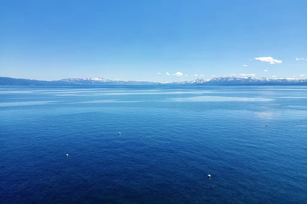 Serenity of the Blue Horizon: A Tranquil Lake View with Majestic Mountains in the Distance