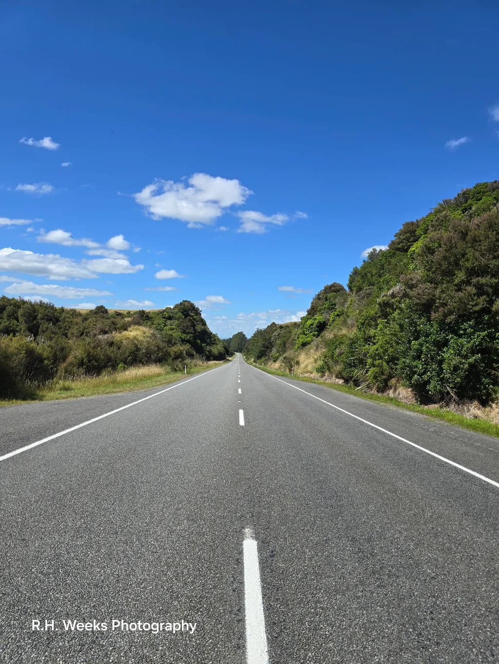 Endless Journey: A Serene Road Beneath a Vast Blue Sky