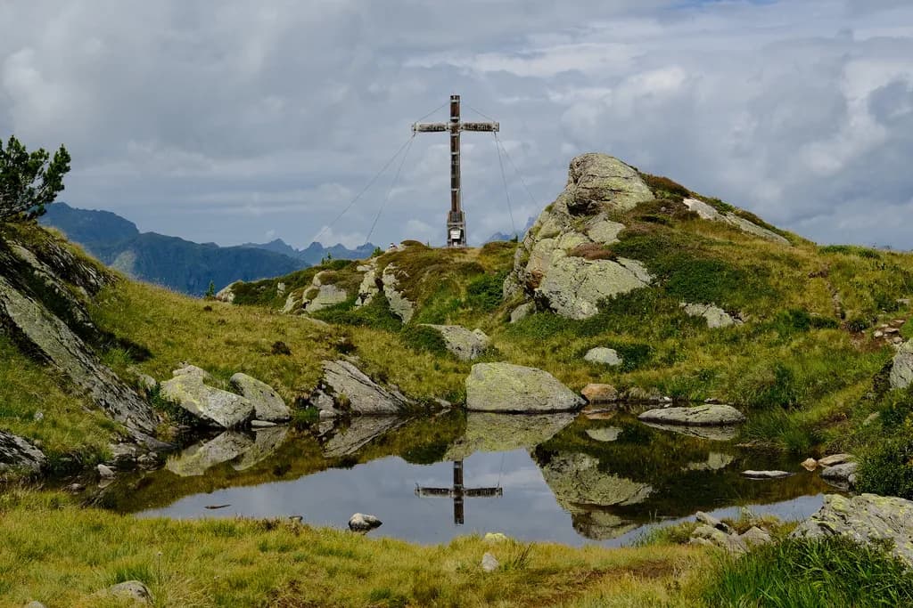 Serenity in Reflection: A Mountain Cross Amidst Nature's Embrace