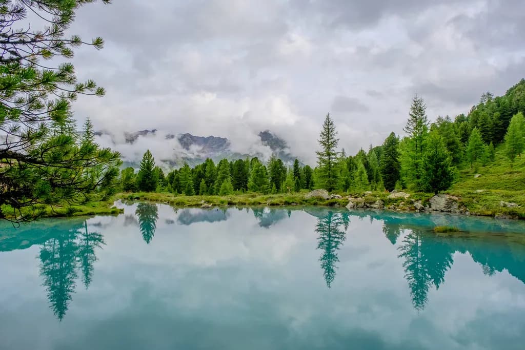 Serenity Reflected: A Tranquil Alpine Lake Amidst Misty Mountains
