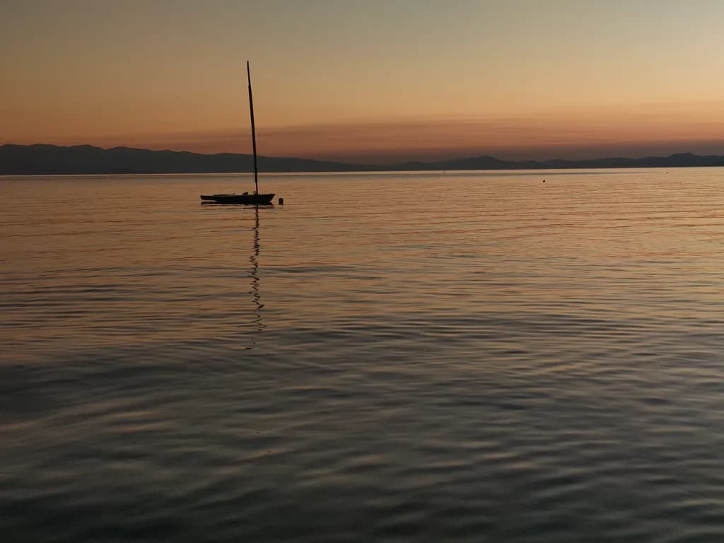 Serenity at Dusk: A Solitary Sailboat on Tranquil Waters