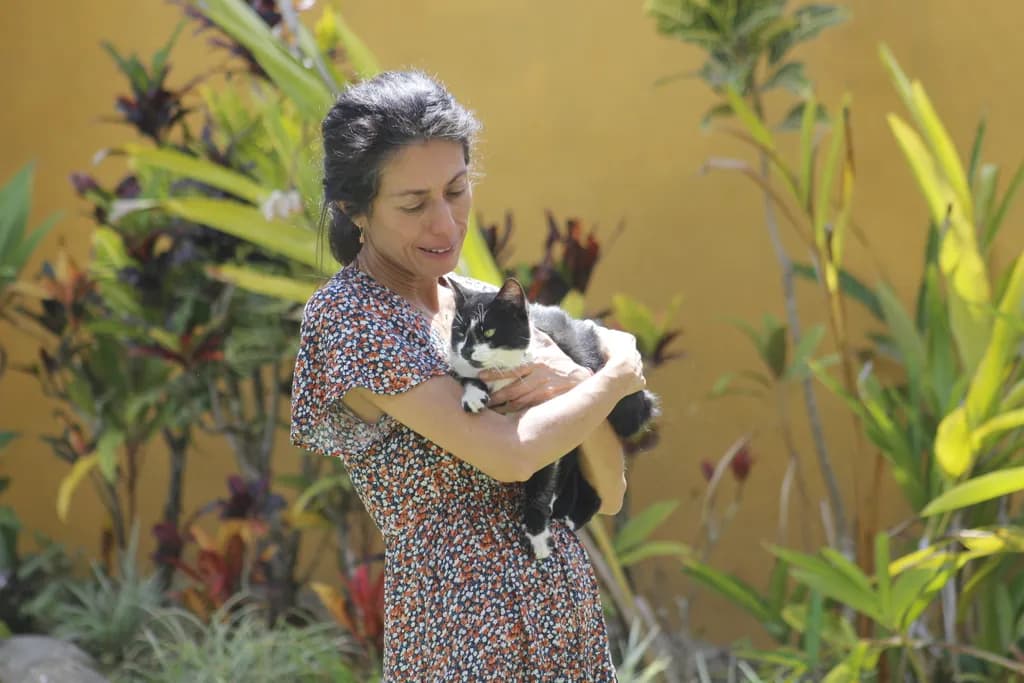 Embracing Serenity: A Woman's Bond with Her Cat in a Lush Tropical Oasis