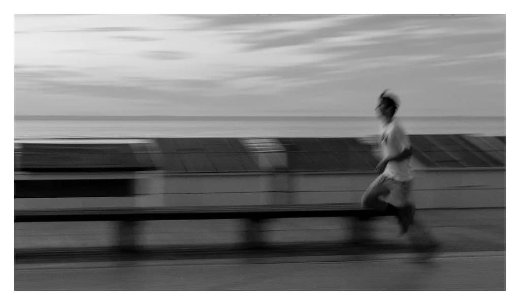 Ethereal Motion: A Monochrome Runner's Journey Along the Coastline