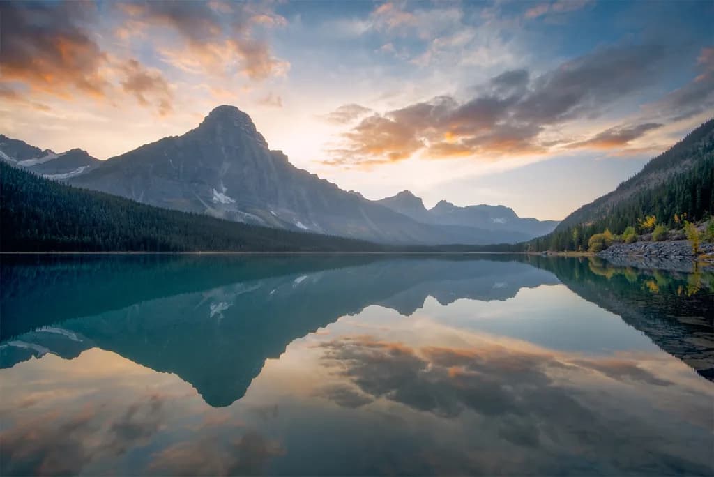 Serenity at Dawn: A Majestic Reflection of Mountains and Sky on Tranquil Waters