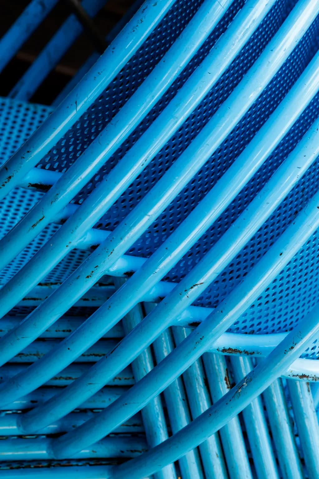 Blue Harmony: A Dance of Stacked Metal Chairs in Textured Patterns