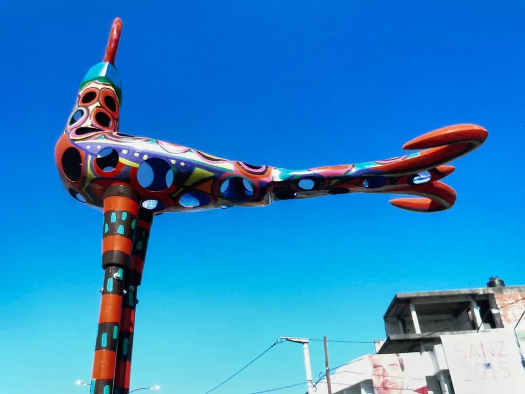 Vibrant Urban Bird: A Colorful Sculpture Against the Sky