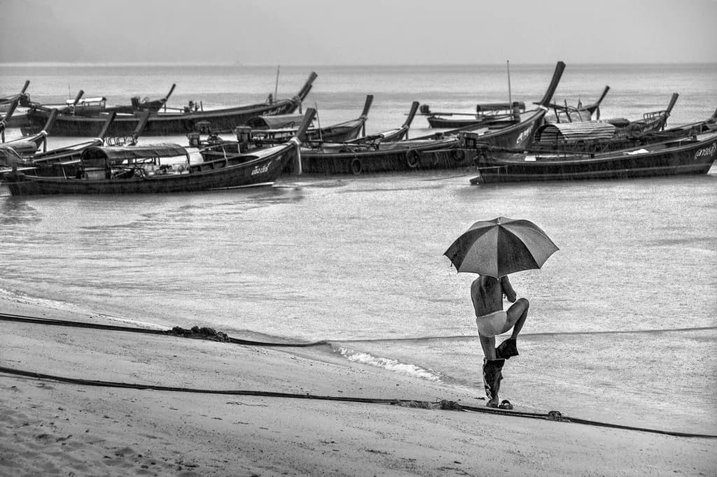 Whispers of Rain: A Solitary Figure Beneath the Umbrella by the Shoreline