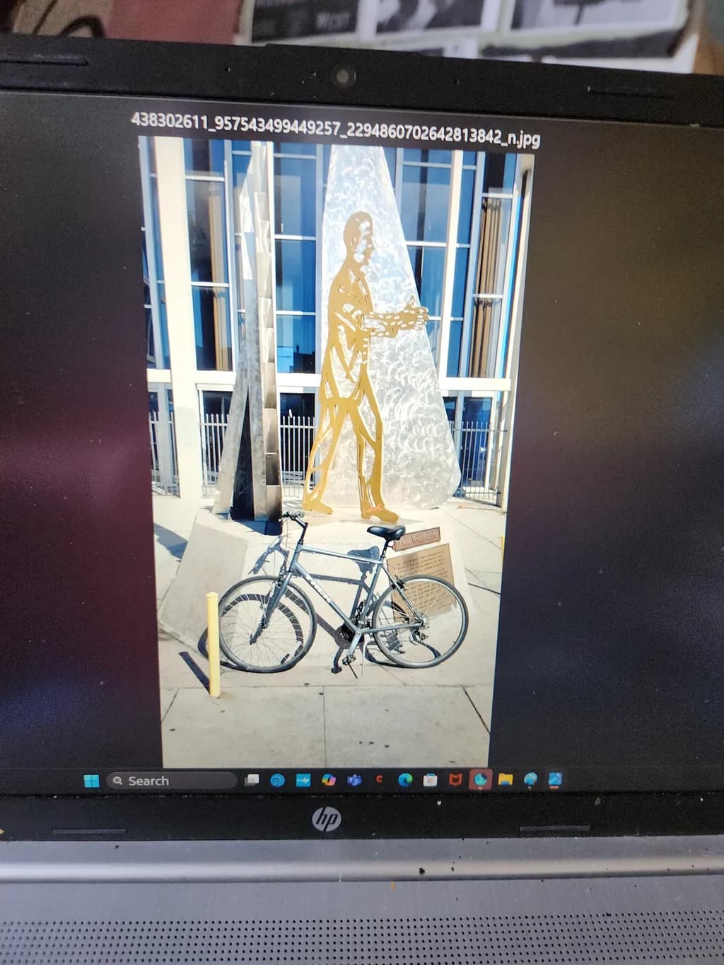 Urban Harmony: A Bicycle's Journey Beside the Golden Sculpture of Progress