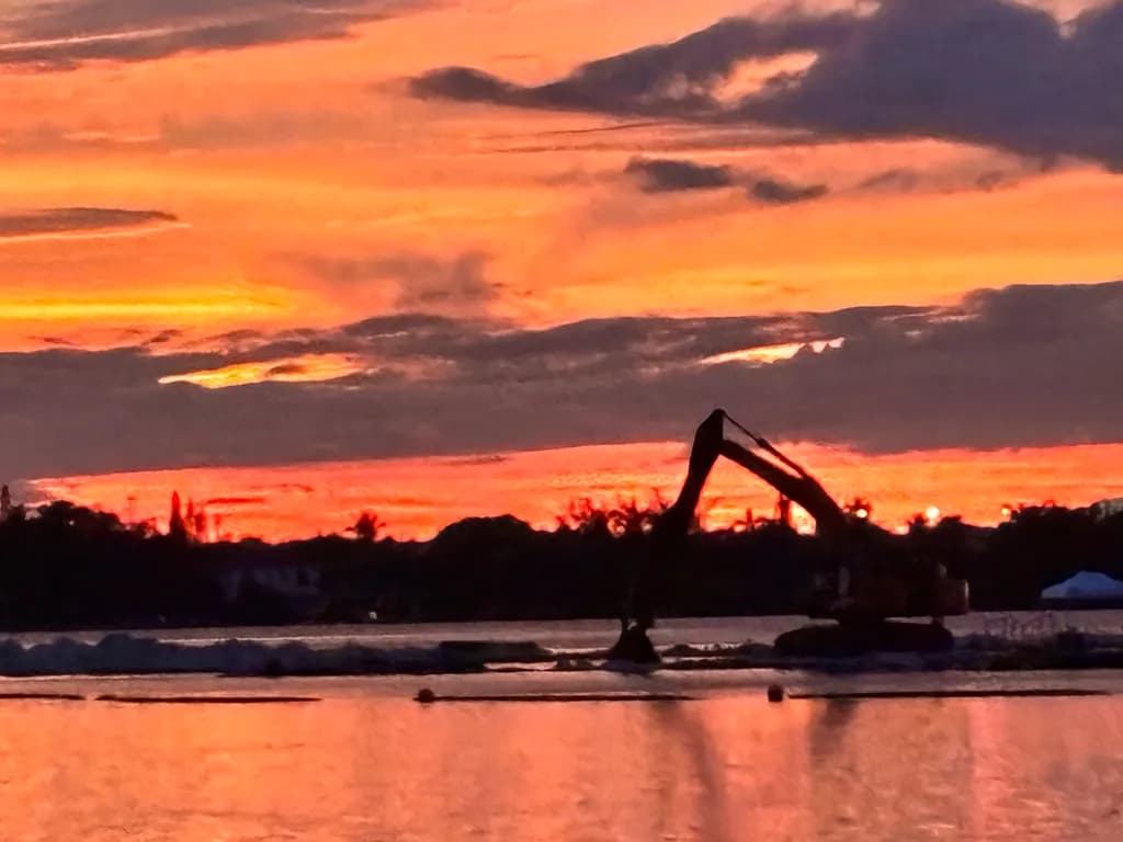 Sunset Reflections: A Digger's Dance on the Water's Edge